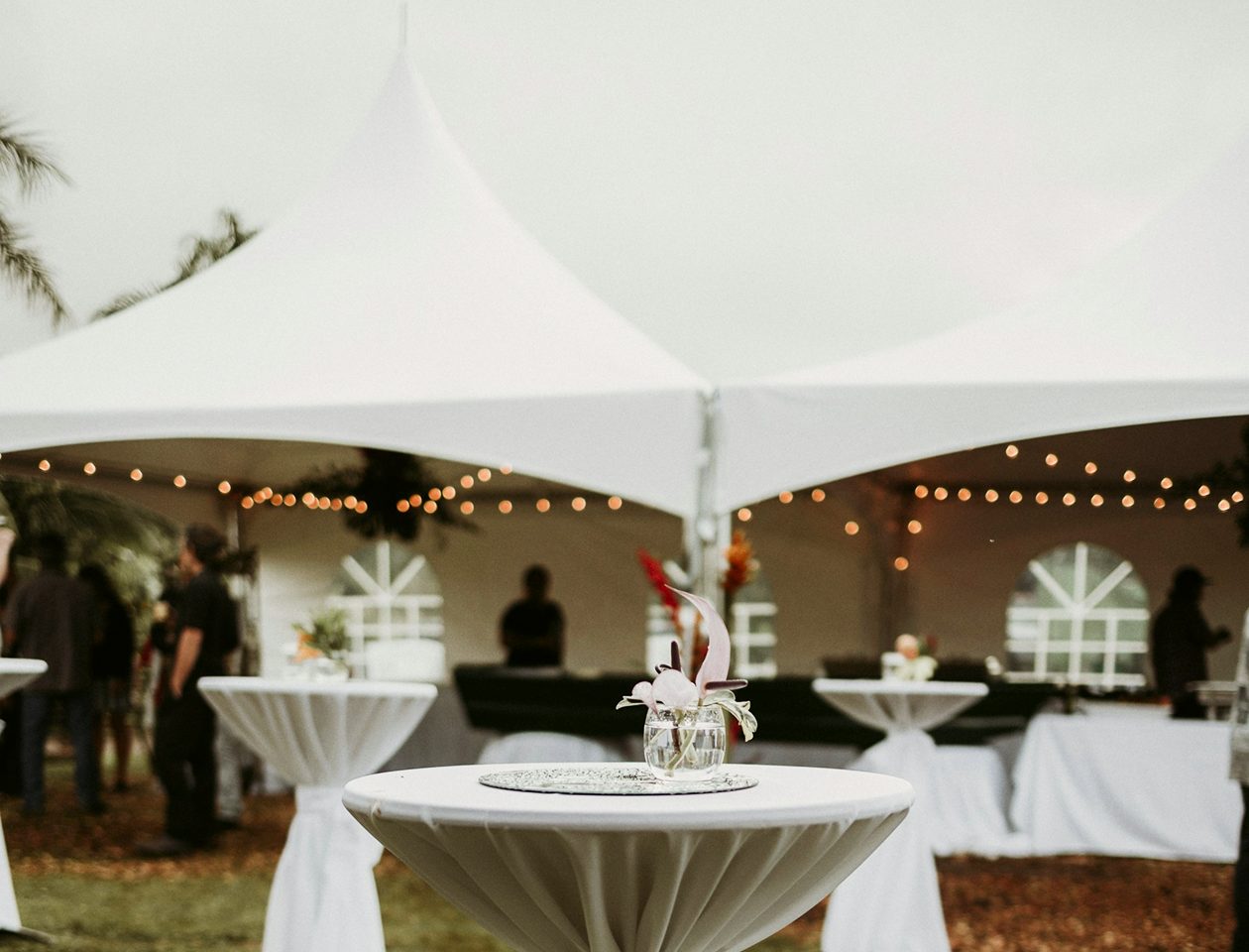 Elegant stretch tent event setup with floral table centerpieces and white canopy